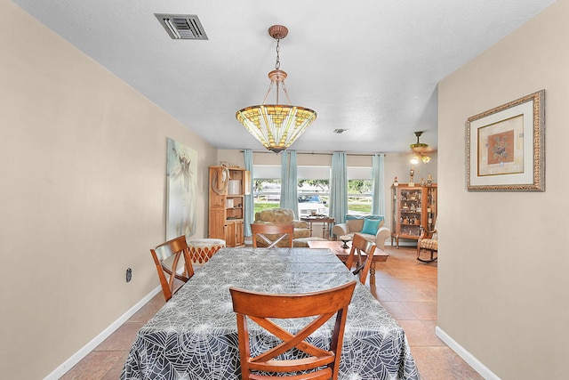 tiled dining room featuring ceiling fan with notable chandelier and a textured ceiling