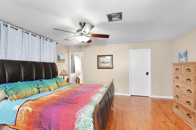 bedroom with a textured ceiling, light wood-type flooring, and ceiling fan