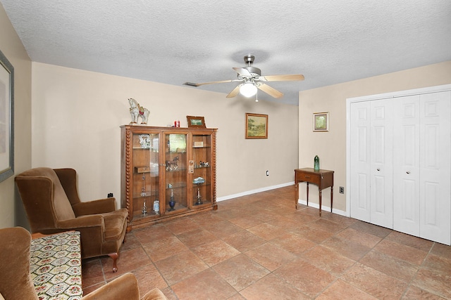 living area featuring a textured ceiling and ceiling fan