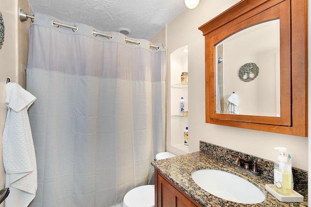 bathroom with curtained shower, vanity, a textured ceiling, and toilet