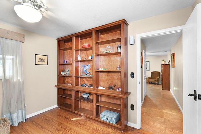 corridor featuring a textured ceiling and light hardwood / wood-style floors