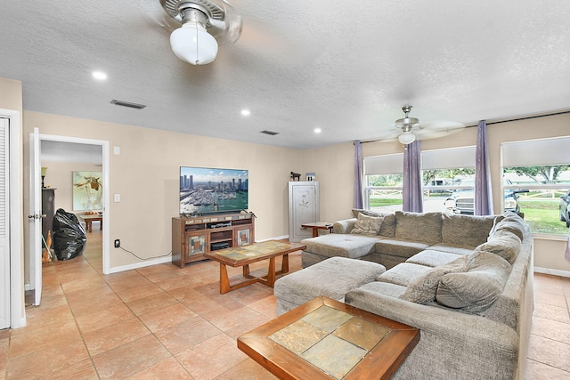 living room with a textured ceiling, ceiling fan, and light tile patterned floors