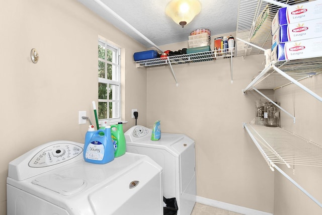 clothes washing area with washing machine and dryer and a textured ceiling