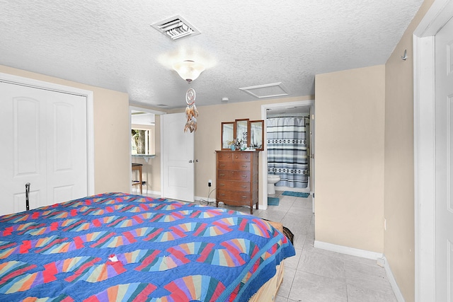 tiled bedroom with connected bathroom, a closet, and a textured ceiling