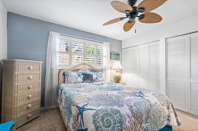 bedroom featuring a textured ceiling, two closets, carpet flooring, and ceiling fan