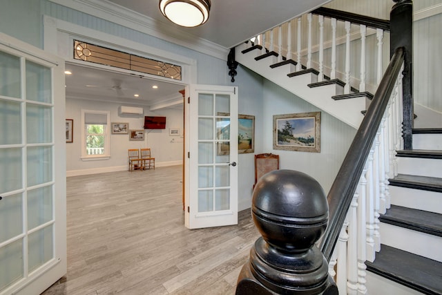 staircase with french doors, a wall mounted AC, crown molding, and hardwood / wood-style floors