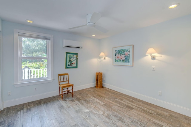 sitting room with ceiling fan, light hardwood / wood-style flooring, and a wall mounted air conditioner