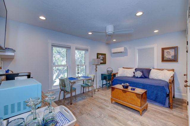 living room with light wood-type flooring, an AC wall unit, and ceiling fan