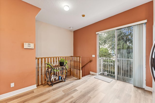 unfurnished room featuring light hardwood / wood-style floors and a textured ceiling