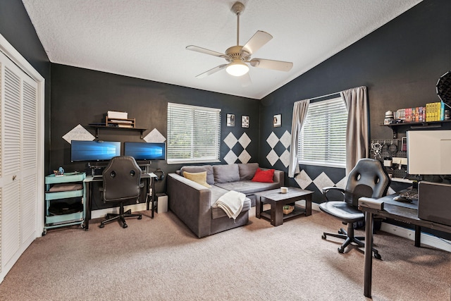 office space with a textured ceiling, vaulted ceiling, carpet flooring, and ceiling fan