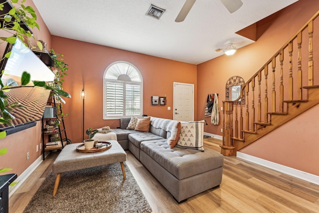 living room with ceiling fan, a textured ceiling, and light hardwood / wood-style flooring