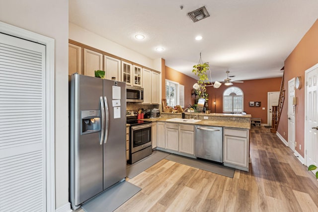 kitchen featuring ceiling fan, appliances with stainless steel finishes, kitchen peninsula, and light wood-type flooring