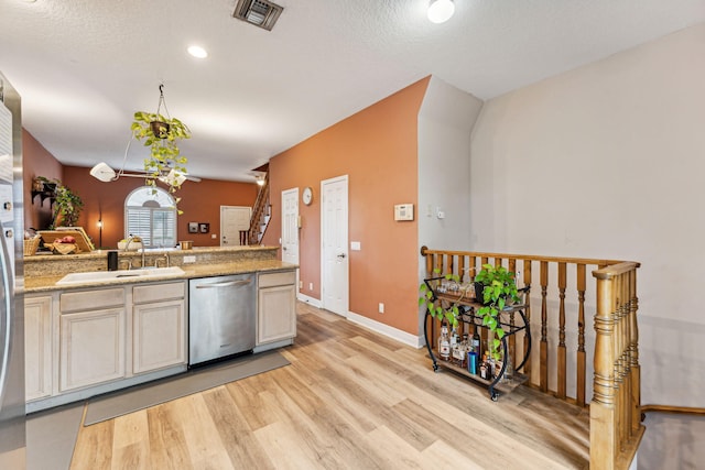 kitchen with stainless steel dishwasher, sink, a textured ceiling, and light hardwood / wood-style floors