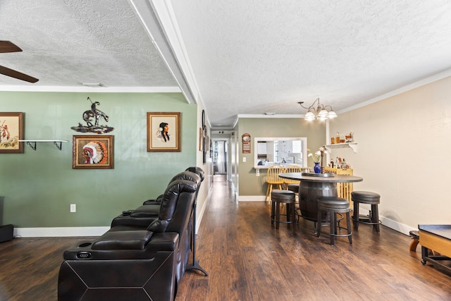 living room with bar area, ceiling fan with notable chandelier, a textured ceiling, dark hardwood / wood-style flooring, and ornamental molding