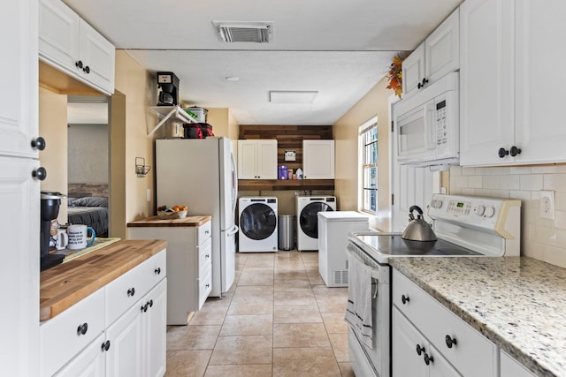 kitchen with white cabinetry, washer and dryer, and white appliances