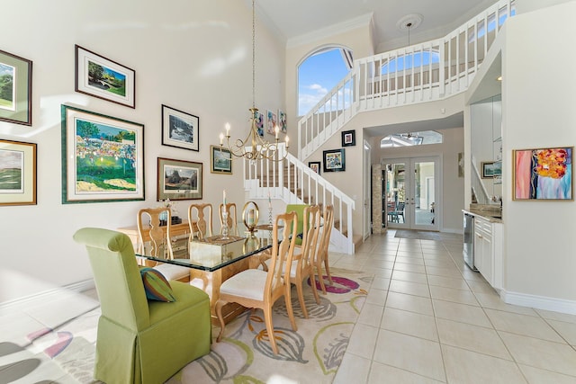 tiled dining space featuring french doors, crown molding, a towering ceiling, and an inviting chandelier