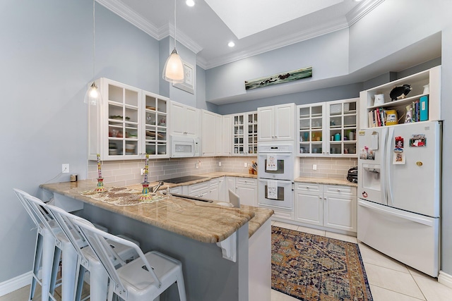 kitchen with a kitchen breakfast bar, hanging light fixtures, kitchen peninsula, white cabinets, and white appliances