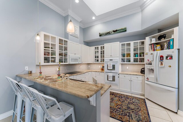 12020 SE Birkdale Run, Jupiter, FL 33469 - kitchen with crown molding, white appliances, a breakfast bar area, a peninsula, and backsplash