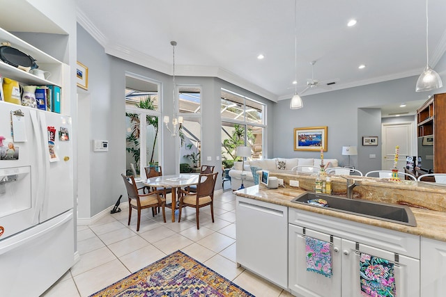 kitchen featuring white appliances, sink, hanging light fixtures, white cabinetry, and ornamental molding