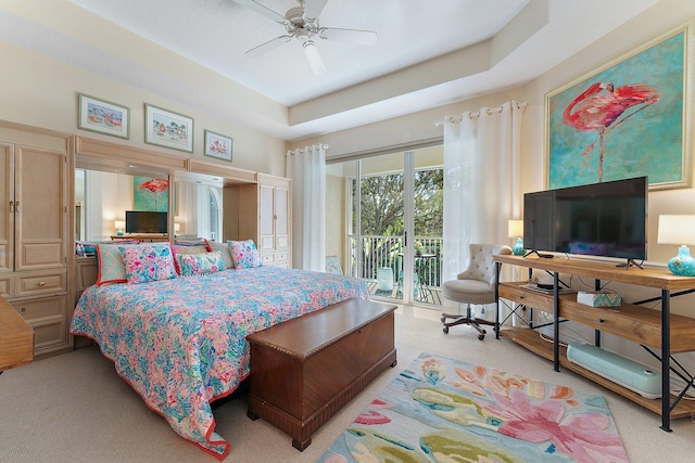 carpeted bedroom featuring access to exterior, a raised ceiling, and ceiling fan