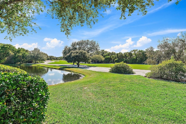 surrounding community with a water view and a lawn