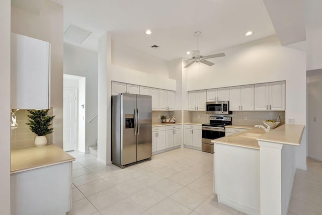 kitchen with a high ceiling, white cabinets, light tile patterned floors, and stainless steel appliances