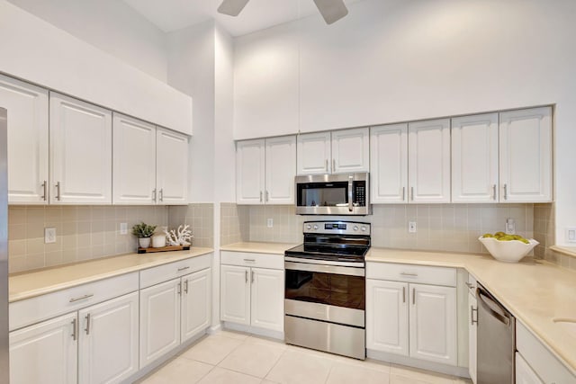 kitchen featuring backsplash, appliances with stainless steel finishes, light tile patterned floors, white cabinets, and ceiling fan