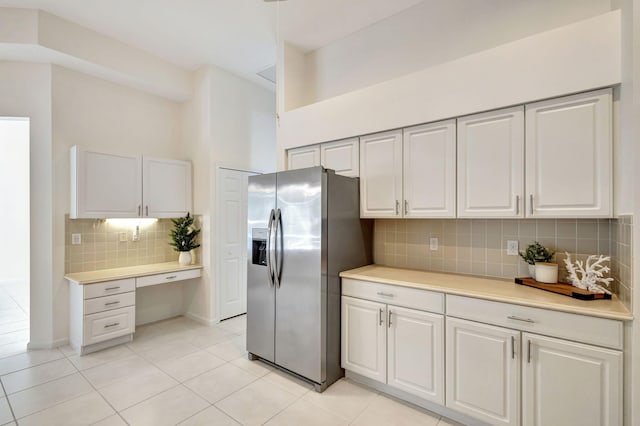 kitchen with white cabinetry, decorative backsplash, light tile patterned floors, and stainless steel fridge