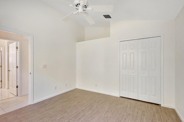 unfurnished bedroom featuring light hardwood / wood-style flooring, ceiling fan, vaulted ceiling, and a closet