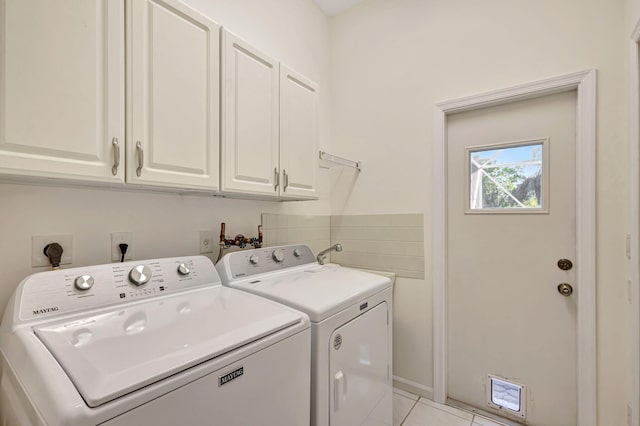 laundry area featuring cabinets, light tile patterned floors, and independent washer and dryer