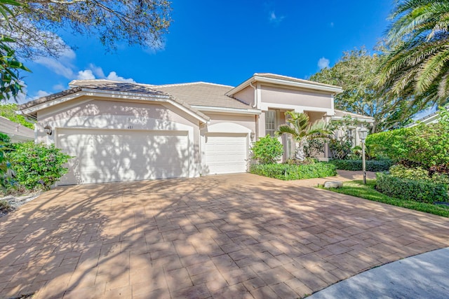6481 Spartina Cir, Jupiter, FL 33458 - view of front of house with an attached garage, driveway, stucco siding, and a tile roof