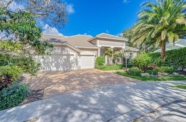 6481 Spartina Cir, Jupiter, FL 33458 - view of front of house with driveway, an attached garage, stucco siding, and a tiled roof