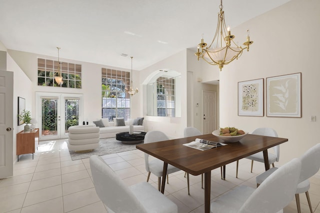 tiled dining space with french doors, a notable chandelier, and a high ceiling