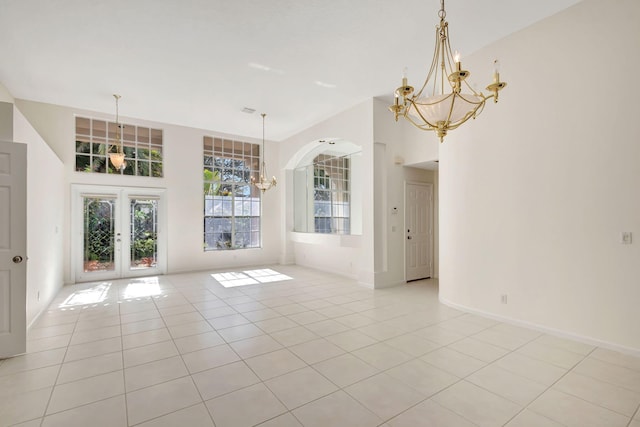 tiled empty room with french doors and a notable chandelier