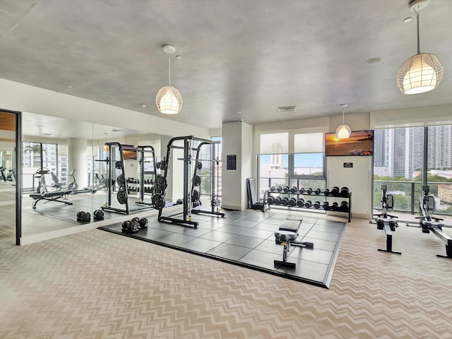 exercise room with light colored carpet and a wealth of natural light