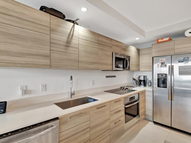 kitchen featuring light brown cabinetry, sink, appliances with stainless steel finishes, and light tile patterned floors