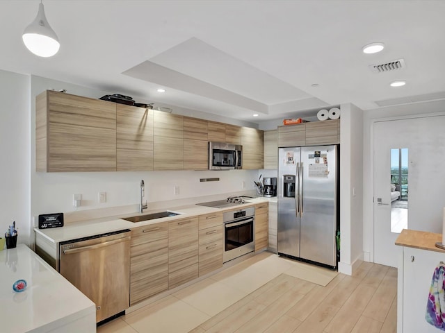 kitchen featuring appliances with stainless steel finishes, light brown cabinets, sink, and light wood-type flooring