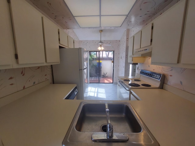 kitchen featuring white cabinets, sink, hanging light fixtures, and white appliances