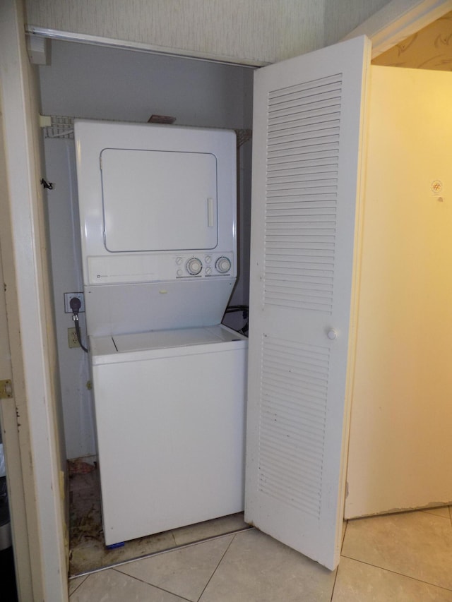 laundry room featuring stacked washer / dryer and light tile patterned flooring