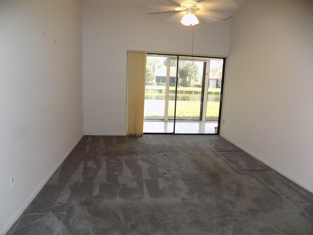 empty room with ceiling fan and dark colored carpet