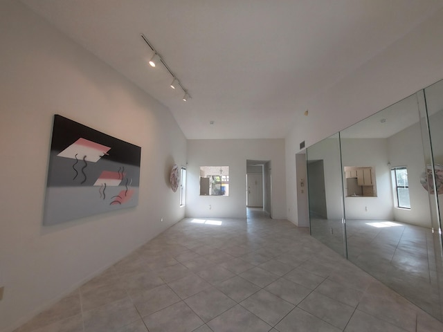 interior space featuring vaulted ceiling, track lighting, and light tile patterned flooring