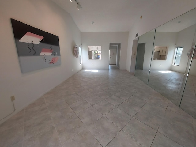 interior space with track lighting, vaulted ceiling, and light tile patterned floors