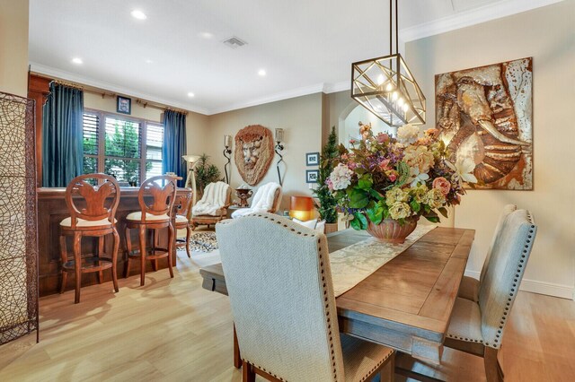 dining room with light wood-type flooring and crown molding