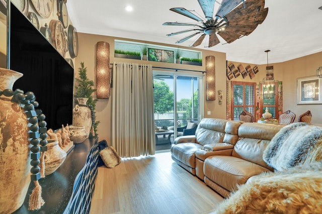 living room featuring ceiling fan with notable chandelier and light wood-type flooring