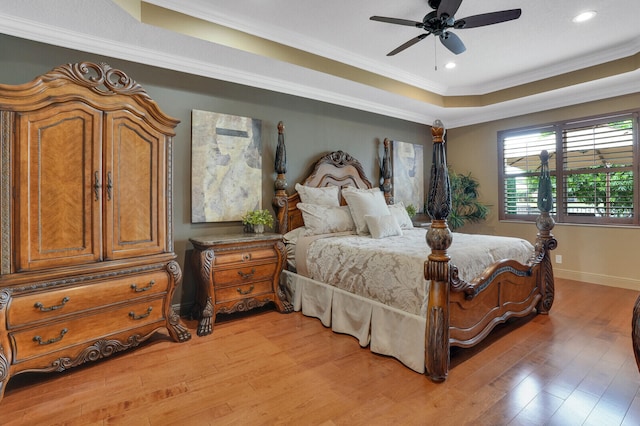 bedroom with light hardwood / wood-style flooring, a raised ceiling, ceiling fan, and ornamental molding