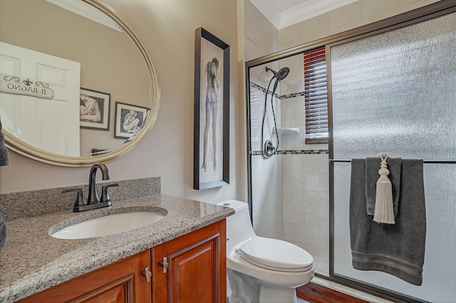 bathroom featuring vanity, toilet, a shower with door, and crown molding