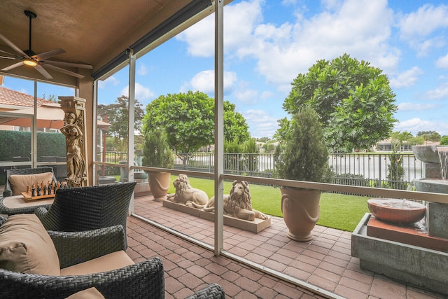 sunroom / solarium with a water view and ceiling fan