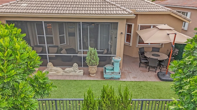 rear view of house with a sunroom, a patio, and a lawn