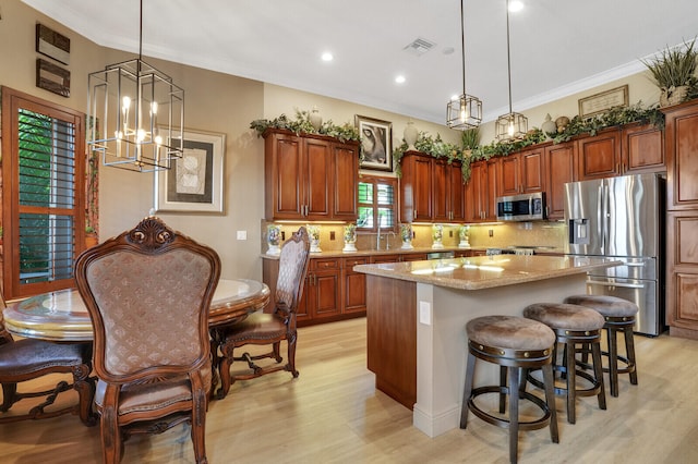 kitchen featuring a chandelier, appliances with stainless steel finishes, a kitchen island, and hanging light fixtures