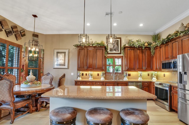 kitchen with sink, hanging light fixtures, stainless steel appliances, a breakfast bar area, and a kitchen island